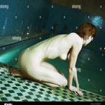 Nude woman kneeling by side of swimming pool side view Stock Photo